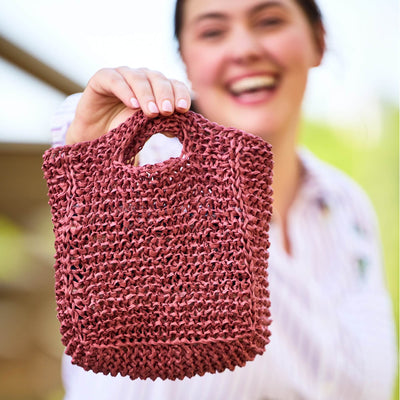 Hand-knit bug bag featuring a colorful beetle motif on a mustard background